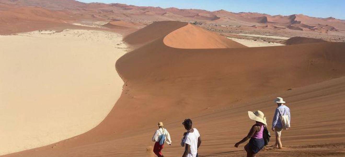 Reisende wandern durch die Dünenlandschaft der Namib in Namibia