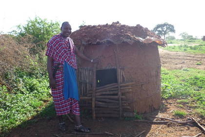Ein Massai vor einer selbstgebauten Hütte