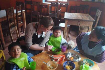 Volunteer with children eating at the women's shelter in Cusco