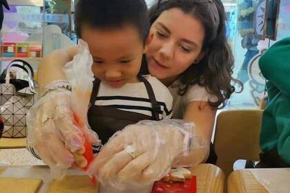 Volunteer macht Lebkuchenhaus mit Kind